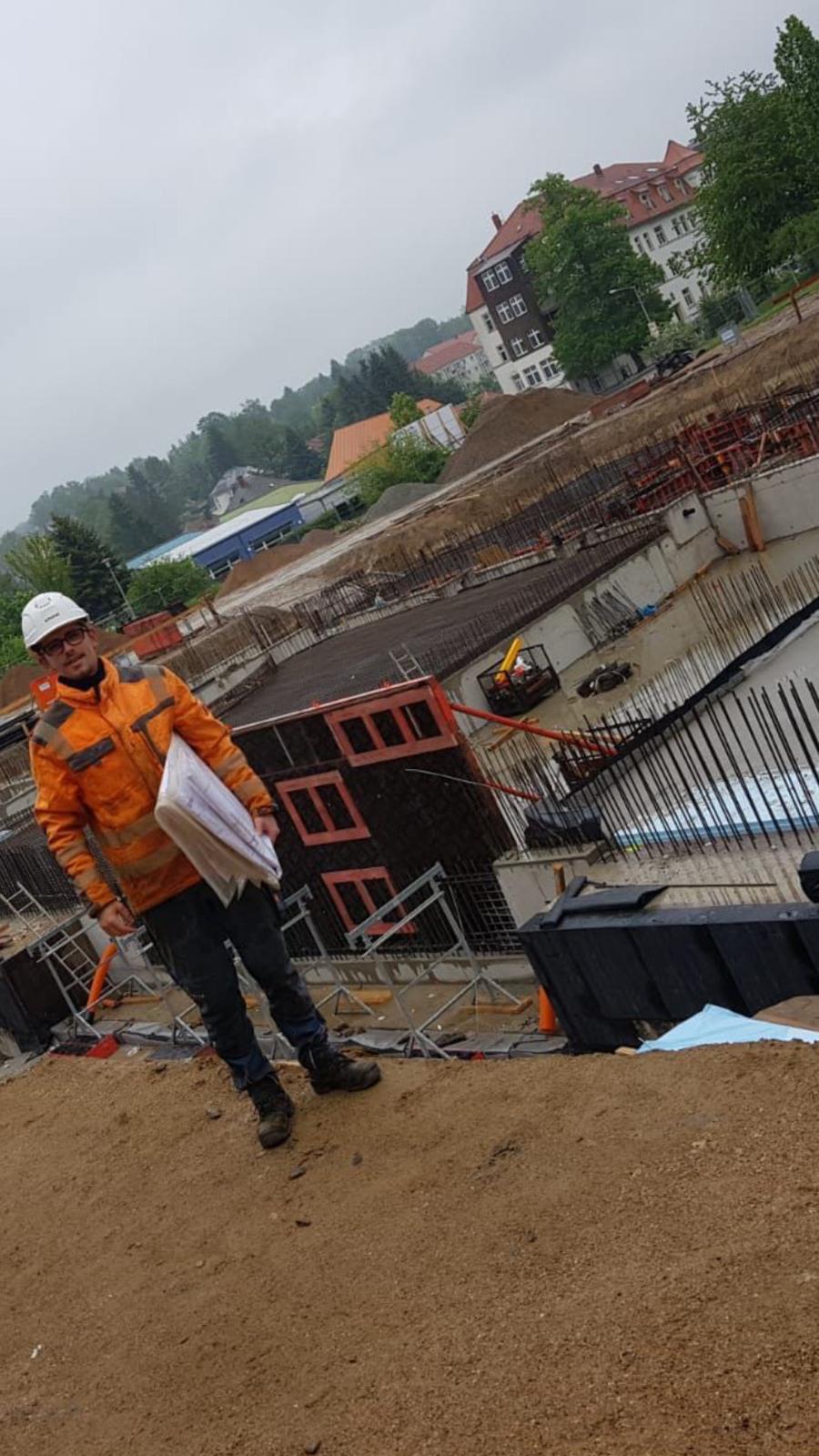 Selim Veliu standing at an active construction site with drawings